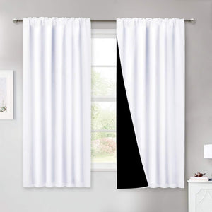 White blackout curtains with rod pocket top, revealing a dark lining, hung on a window rod.