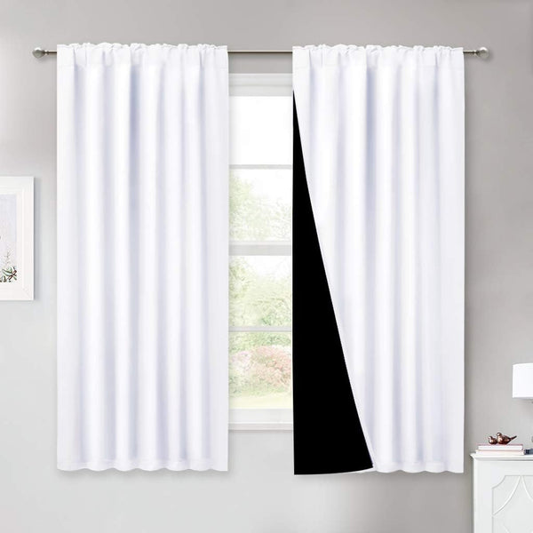 White blackout curtains with rod pocket top, revealing a dark lining, hung on a window rod.