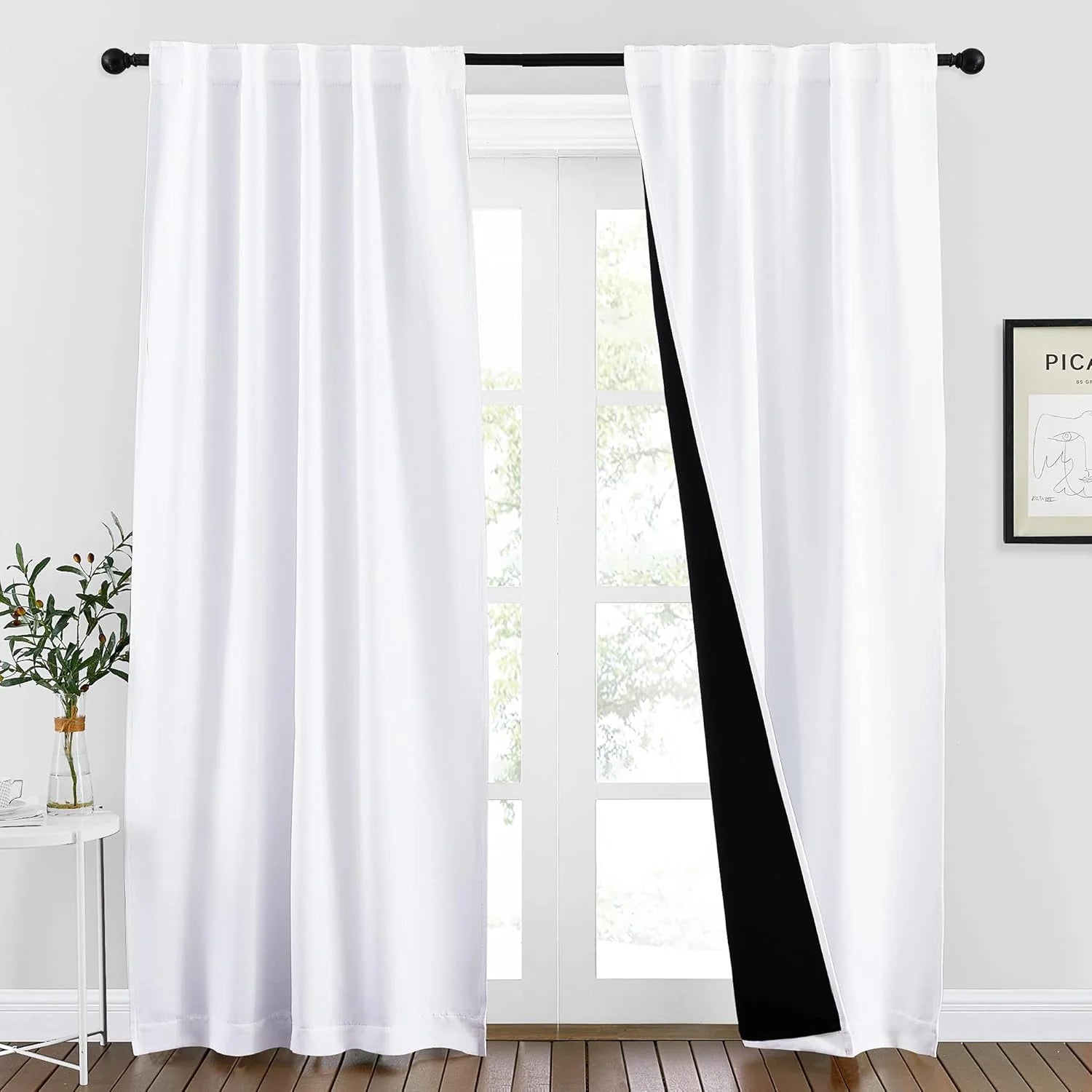 White rod pocket blackout curtains on a black curtain rod in a bright modern room