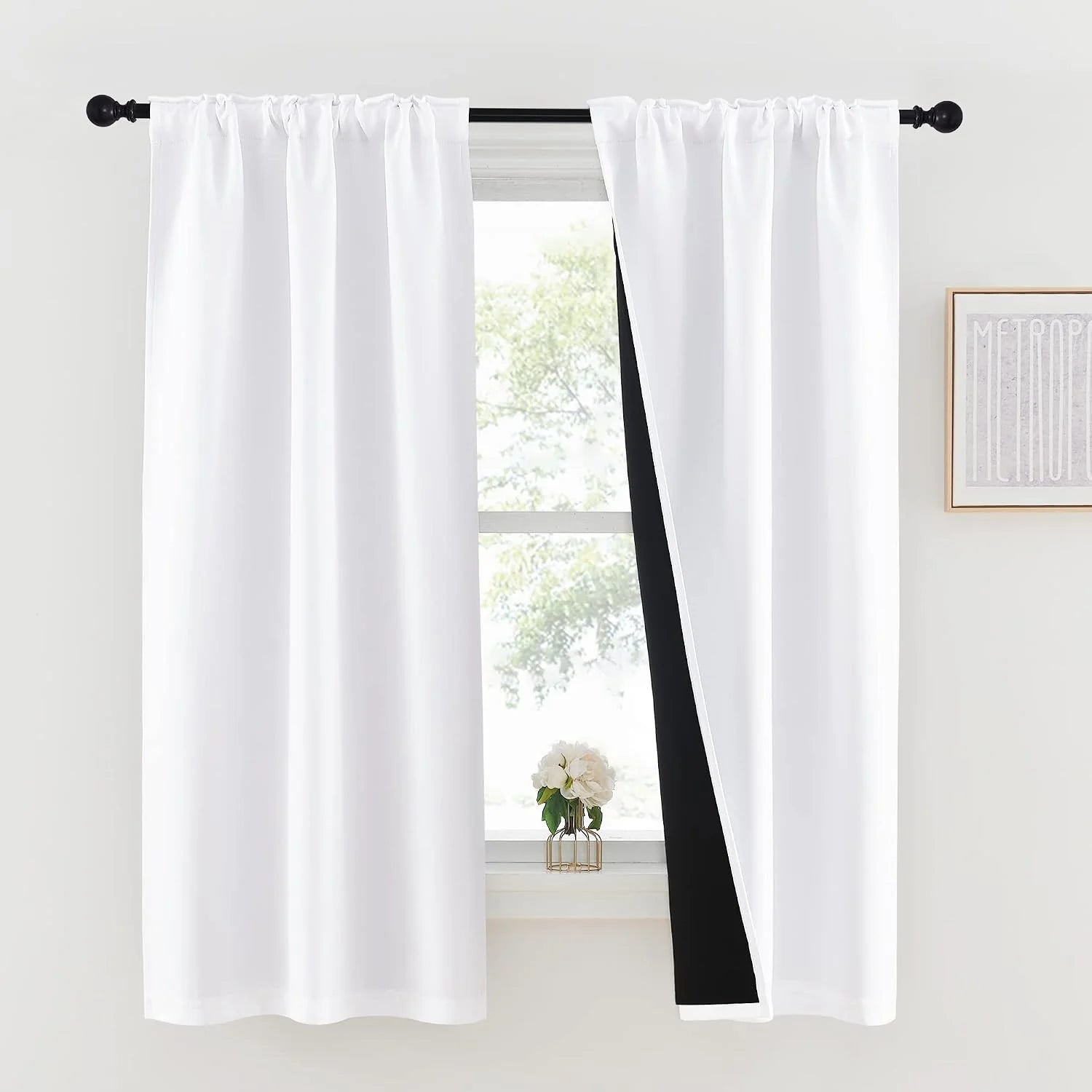 White rod pocket blackout curtains on a black curtain rod in a bright window