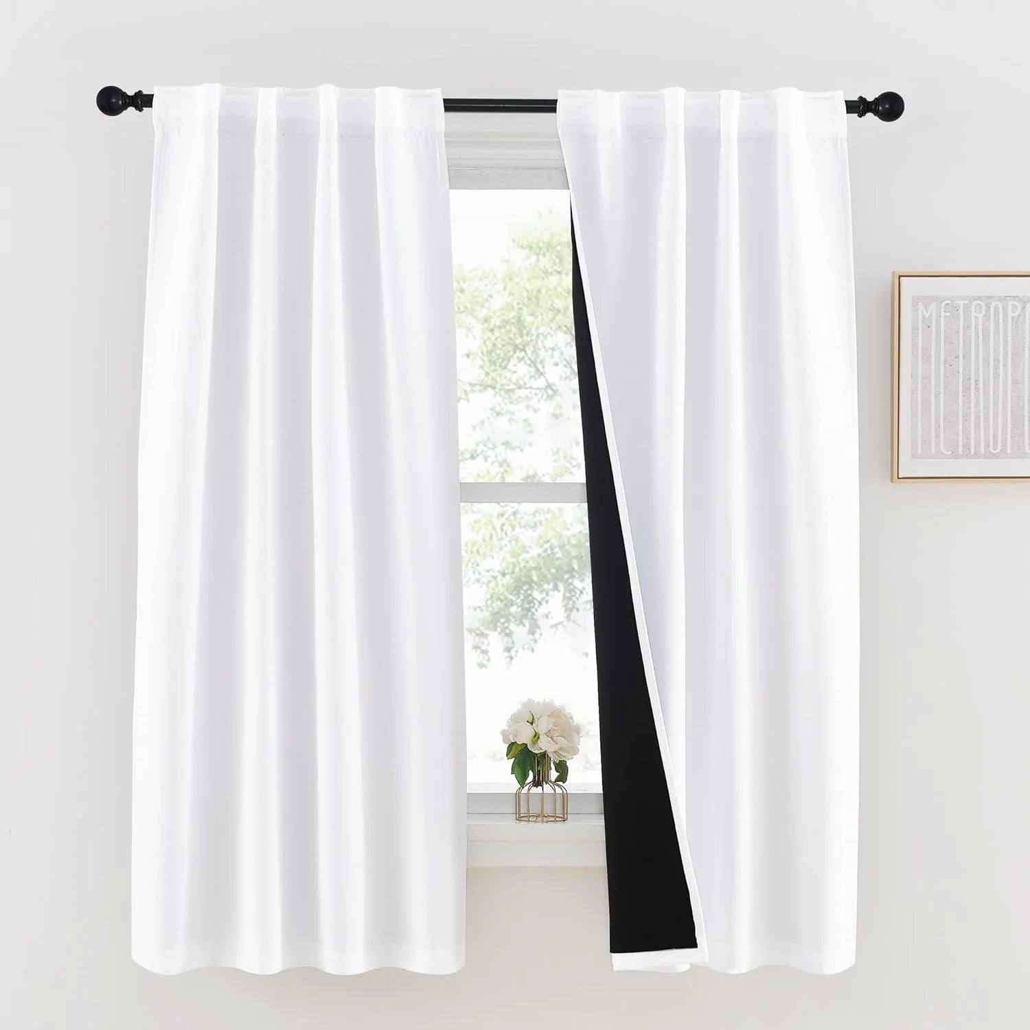 White rod pocket blackout curtains on a black curtain rod in a bright modern room