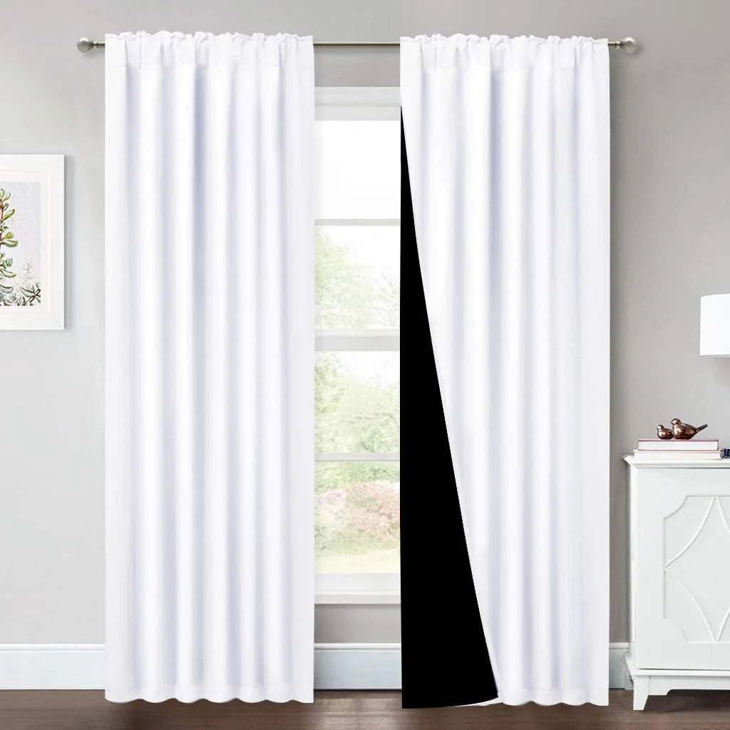 White blackout curtains on a silver rod in a bright modern room with black lining visible