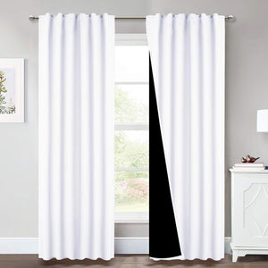 Clean white blackout curtains hanging on a silver rod, revealing a dark lining for total room darkening.