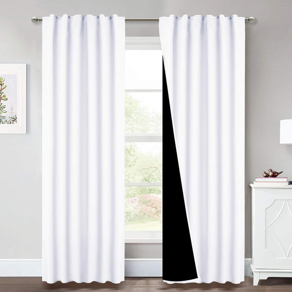 Clean white blackout curtains hanging on a silver rod, revealing a dark lining for total room darkening.