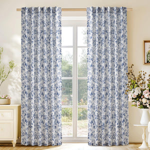 White curtains with intricate blue floral patterns and rod pocket top, hanging in a bright room.