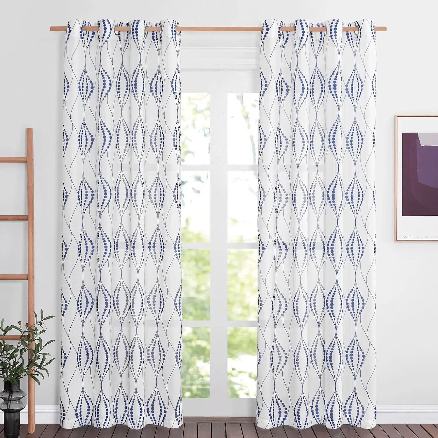 White curtains with blue geometric dotted pattern hanging on a wooden rod by a bright window
