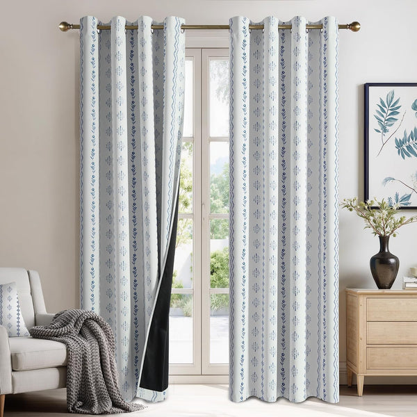 White grommet curtains with vertical blue patterns and black blackout lining, hanging over a window.