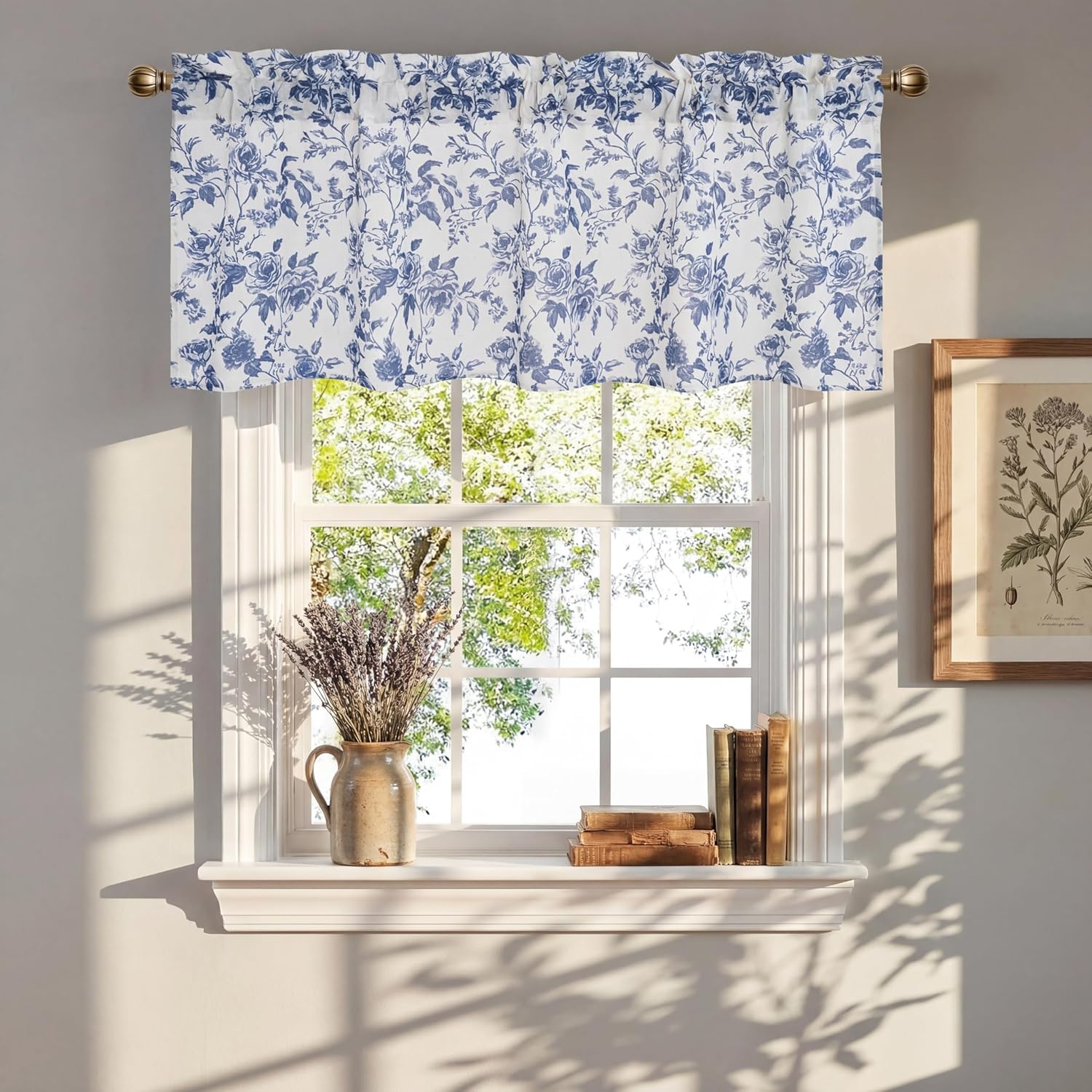 White valance with an intricate blue rose floral pattern, gathered on a brass rod above a window.