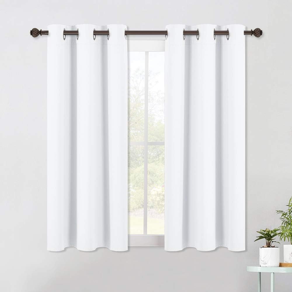 Pair of white blackout cafe tier curtains with silver grommet tops on a dark bronze rod over a window.