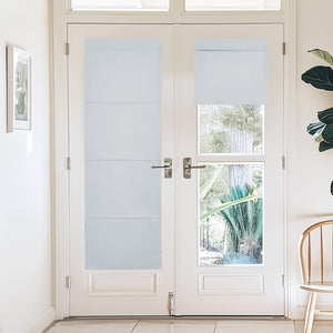 White opaque cordless fabric shades, one extended and one rolled up, on white French doors.