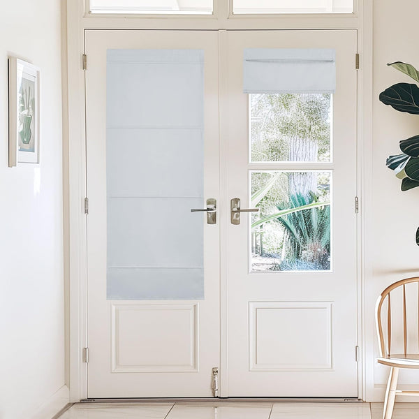 White cordless Roman blackout shades installed on glass French doors; one lowered, another raised, providing light and privacy control.