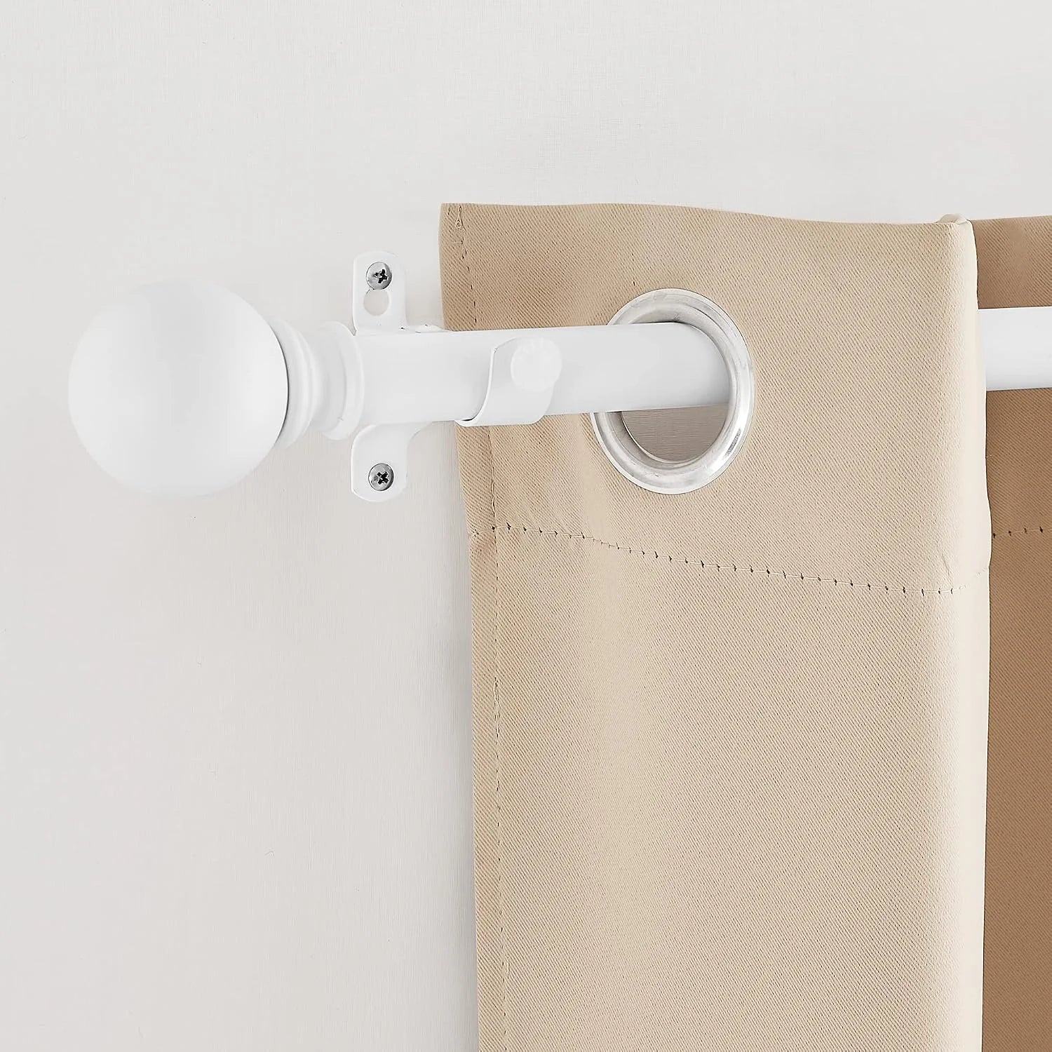 White curtain rod with round finial holding a beige grommet curtain panel