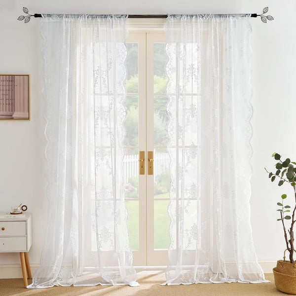 White embroidered sheer curtains with scalloped lace edges, hanging on a rod over glass doors.