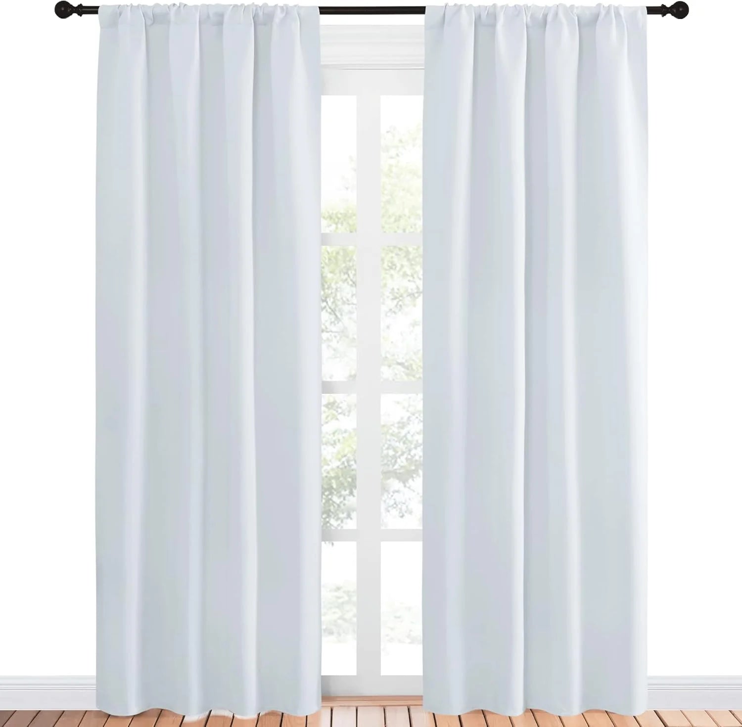 Pair of white fabric rod pocket curtains hanging on a dark rod over a window.