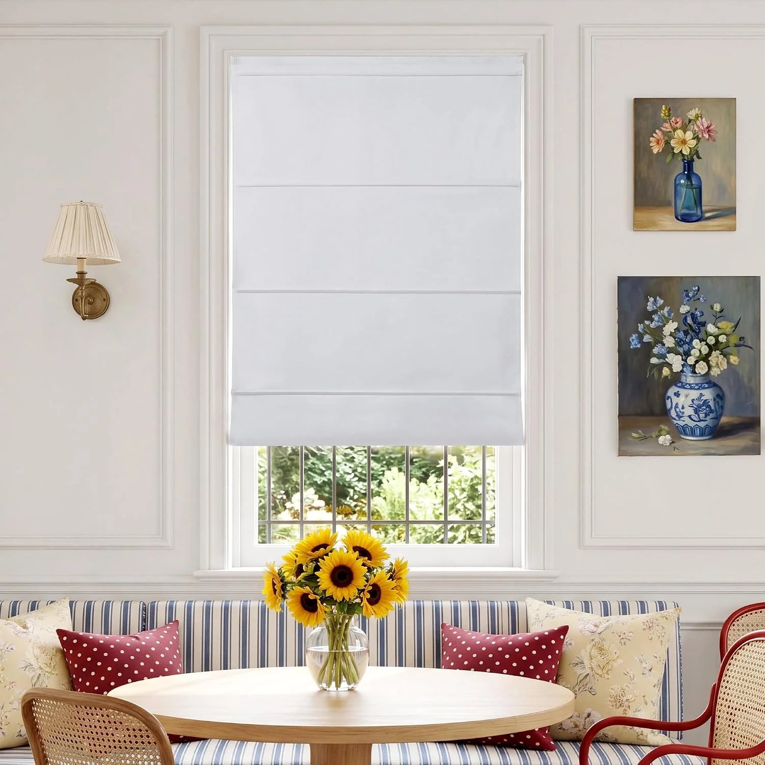 White flat Roman shade on window in cozy dining nook with sunflowers and striped bench.