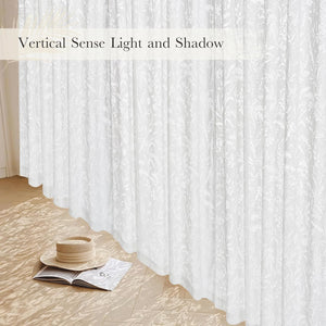 White sheer window curtains with a delicate botanical embroidered pattern, filtering natural light into the room.