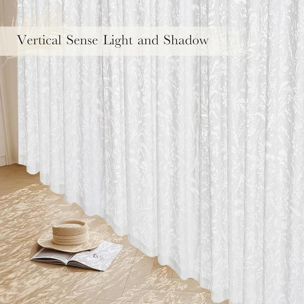 White sheer window curtains with a delicate botanical embroidered pattern, filtering natural light into the room.