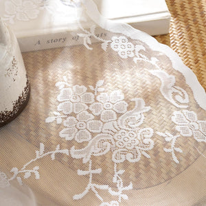 White floral lace table runner with delicate flower patterns, sheer mesh, and scalloped edge.