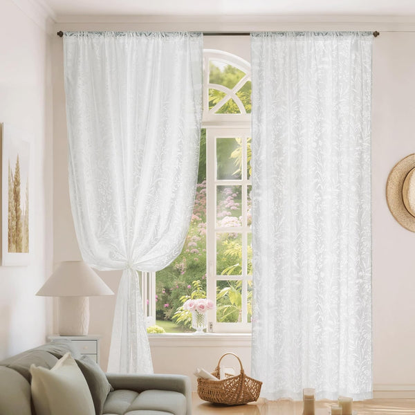 White sheer rod pocket curtains with delicate floral embroidery. One panel tied back revealing a bright garden.