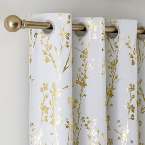 White curtains with a sparkling metallic gold floral pattern hanging from a gold curtain rod with silver grommets.