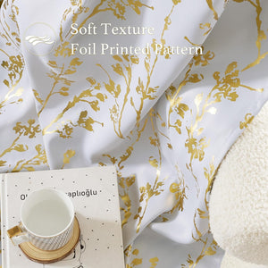 Soft white curtain with elegant gold foil printed botanical pattern. A patterned mug and book are nearby.