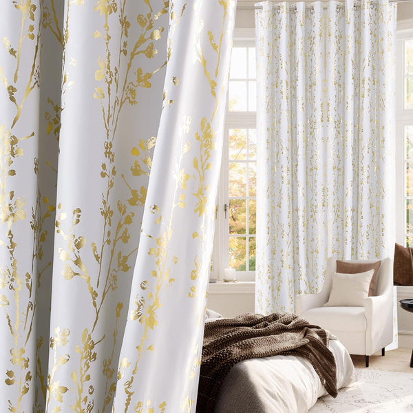 White curtains with metallic gold floral branch pattern and silver grommet top in a bright window.