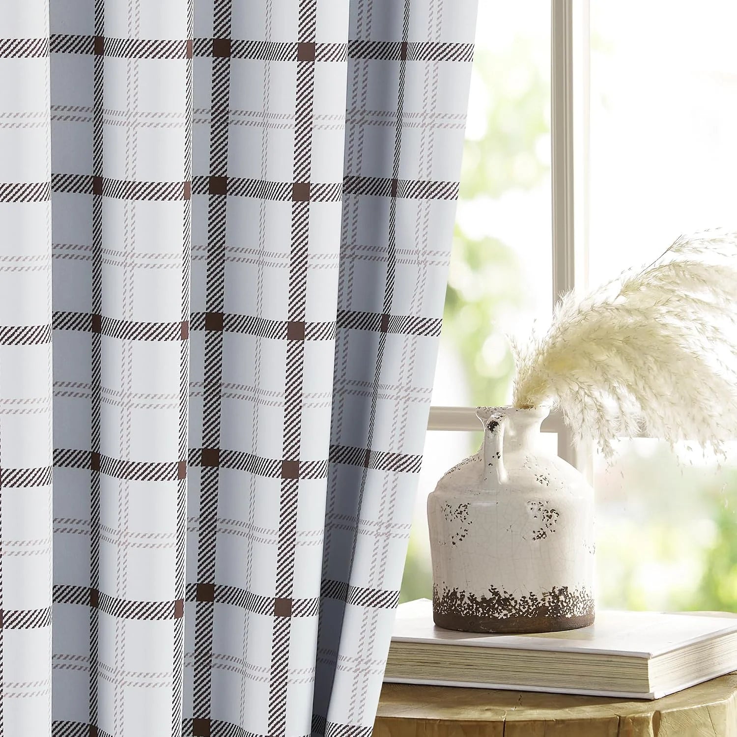 White and gray plaid curtain panel beside a bright window with rustic vase decor