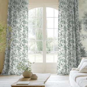 White curtains with a dense green floral rose pattern, hanging in a bright living room.