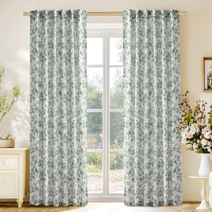 Pair of white curtains with green rose and vine floral pattern, hung on wooden rod.