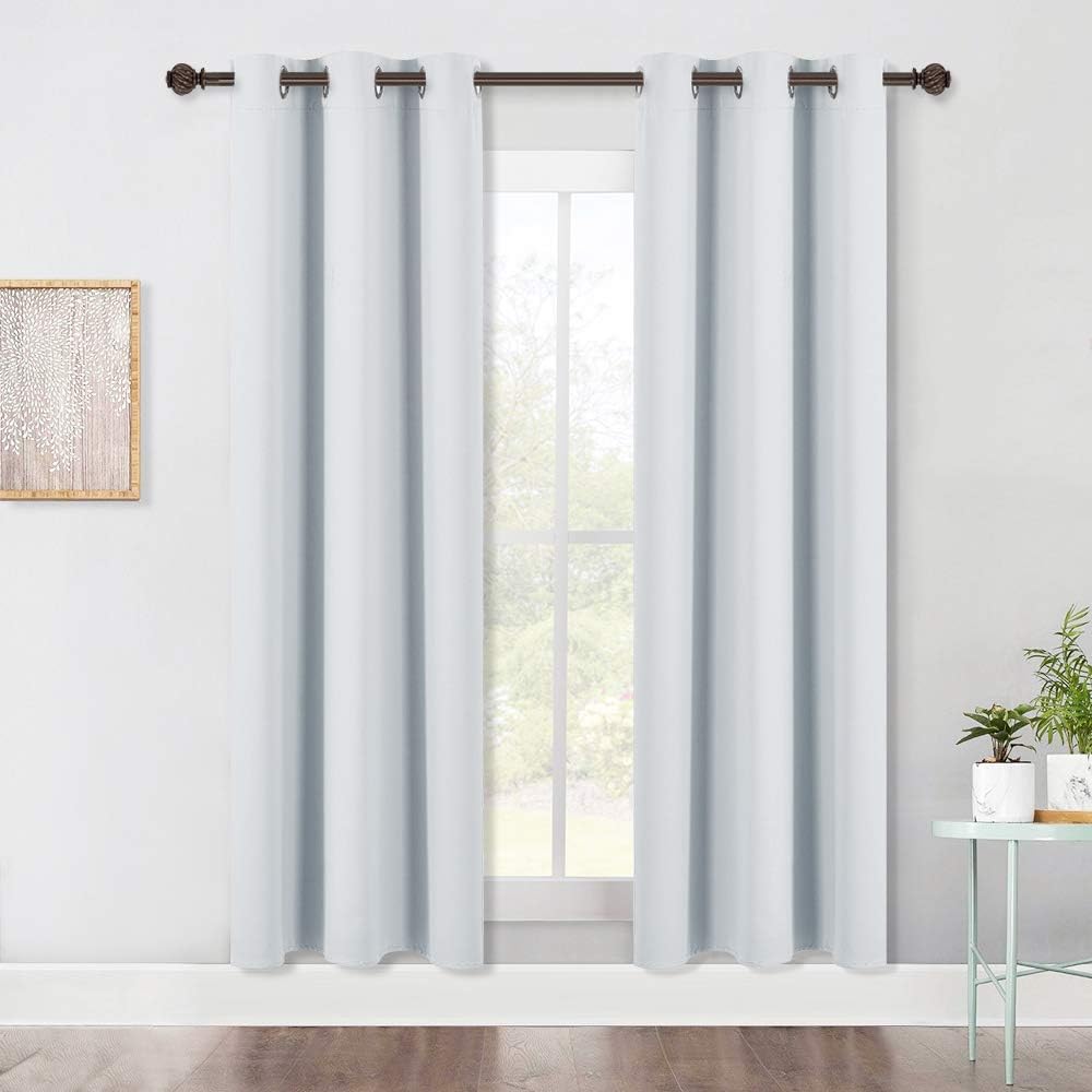 White grommet top curtains on dark rod over window. Thick fabric for privacy and light control.