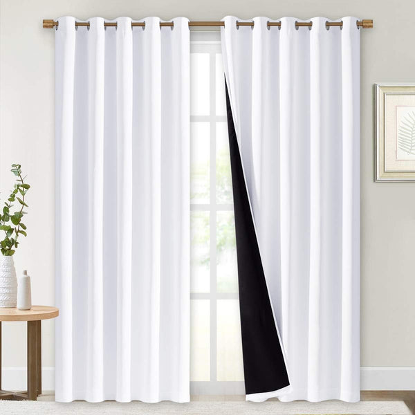 Pair of white grommet curtains with visible black thermal blackout lining on a window.