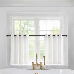 White cafe curtains with black grommets on a black rod above a bathroom window.