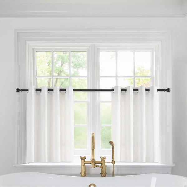 White cafe curtains with black grommets on a black rod above a bathroom window.