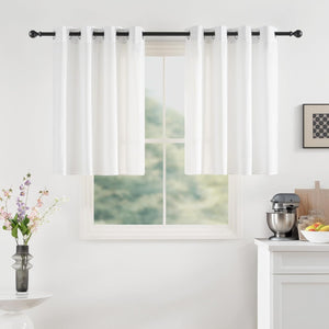 White grommet tier curtains on black rod in a bright kitchen window. Mixer and flowers visible.