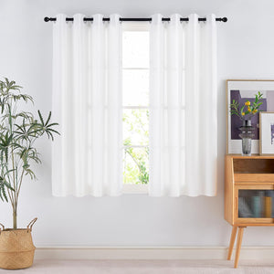 White grommet top curtains providing light filtering over a window, displayed in a modern room.
