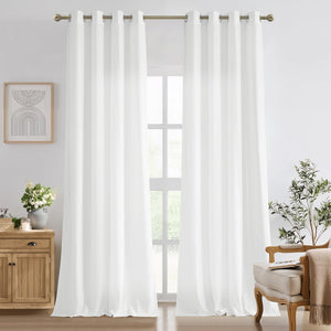 Two panels of white solid grommet top curtains hanging on a brass rod in a bright room.