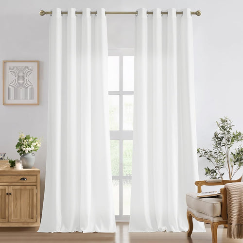 Two panels of white solid grommet top curtains hanging on a brass rod in a bright room.