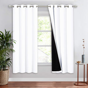 White grommet top blackout curtains on a silver rod, one panel partially open revealing black lining.