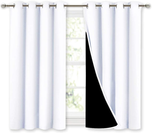 White blackout curtains with silver grommet tops. Right panel slightly pulled back reveals black thermal lining.