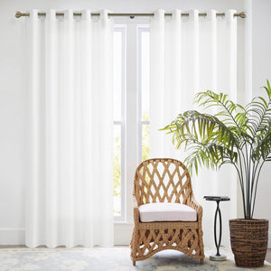 White, solid fabric room darkening curtain panel with grommet top on a bronze rod in a bright room.