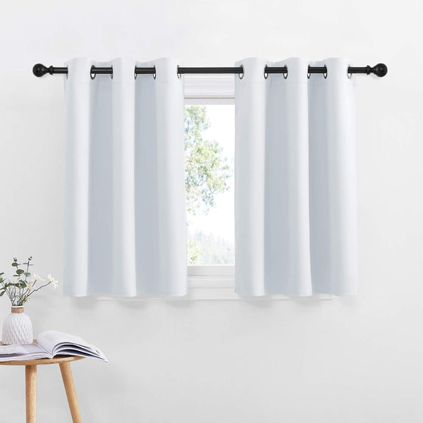 Two smooth white grommet top blackout curtains hung on a black rod over a small window.