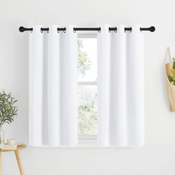 Two bright white grommet top curtains on a black rod, covering a sunlit window frame.