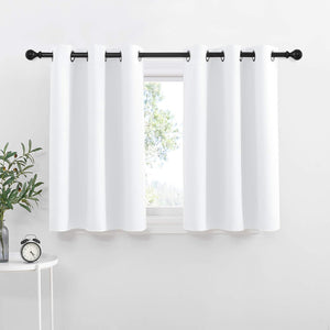 Crisp white tier curtains with black grommet tops hanging on a black rod, enhancing a bright window.