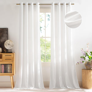 White light filtering curtains with grommet tops on a bronze rod, hanging by a window.