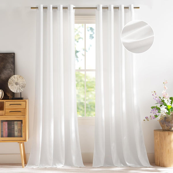 White light filtering curtains with grommet tops on a bronze rod, hanging by a window.