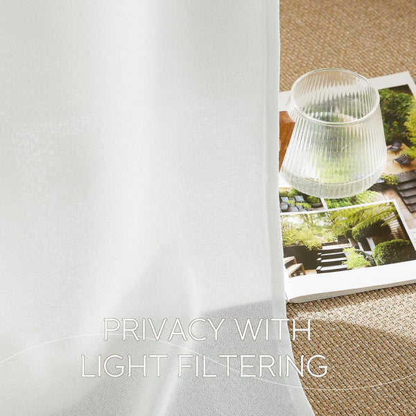 White sheer woven curtain fabric providing privacy and gentle light filtering, seen beside a magazine and water glass.