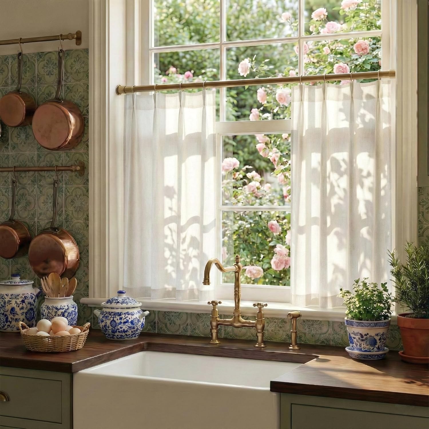 White linen cafe curtains on a brass rod in a charming kitchen window overlooking pink roses.