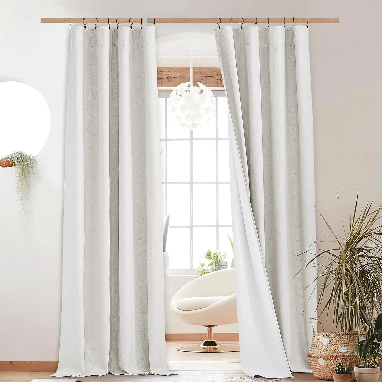 White textured linen curtains hanging from a wooden rod in a bright modern room