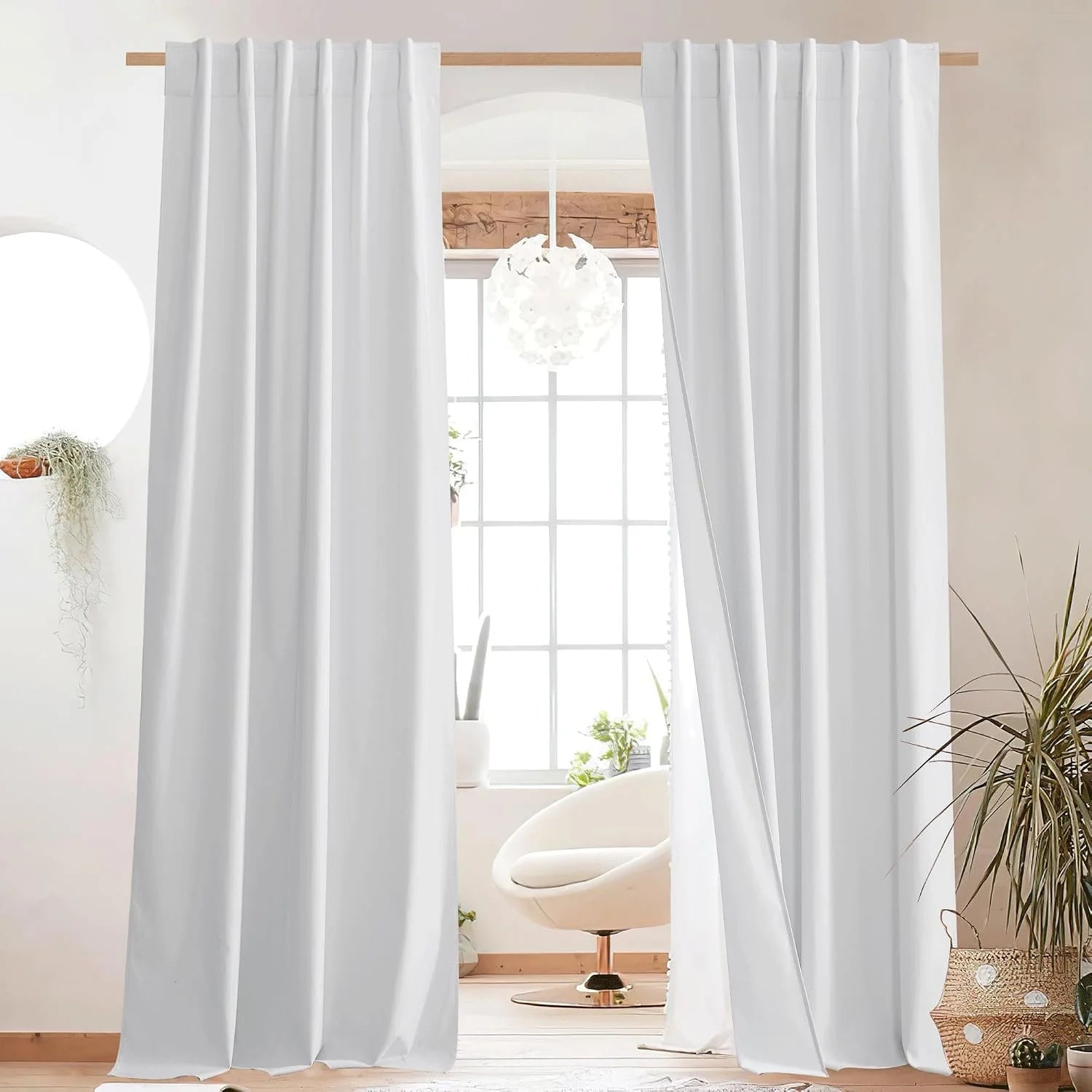 White rod pocket curtains hanging over a bright window in a minimalist room