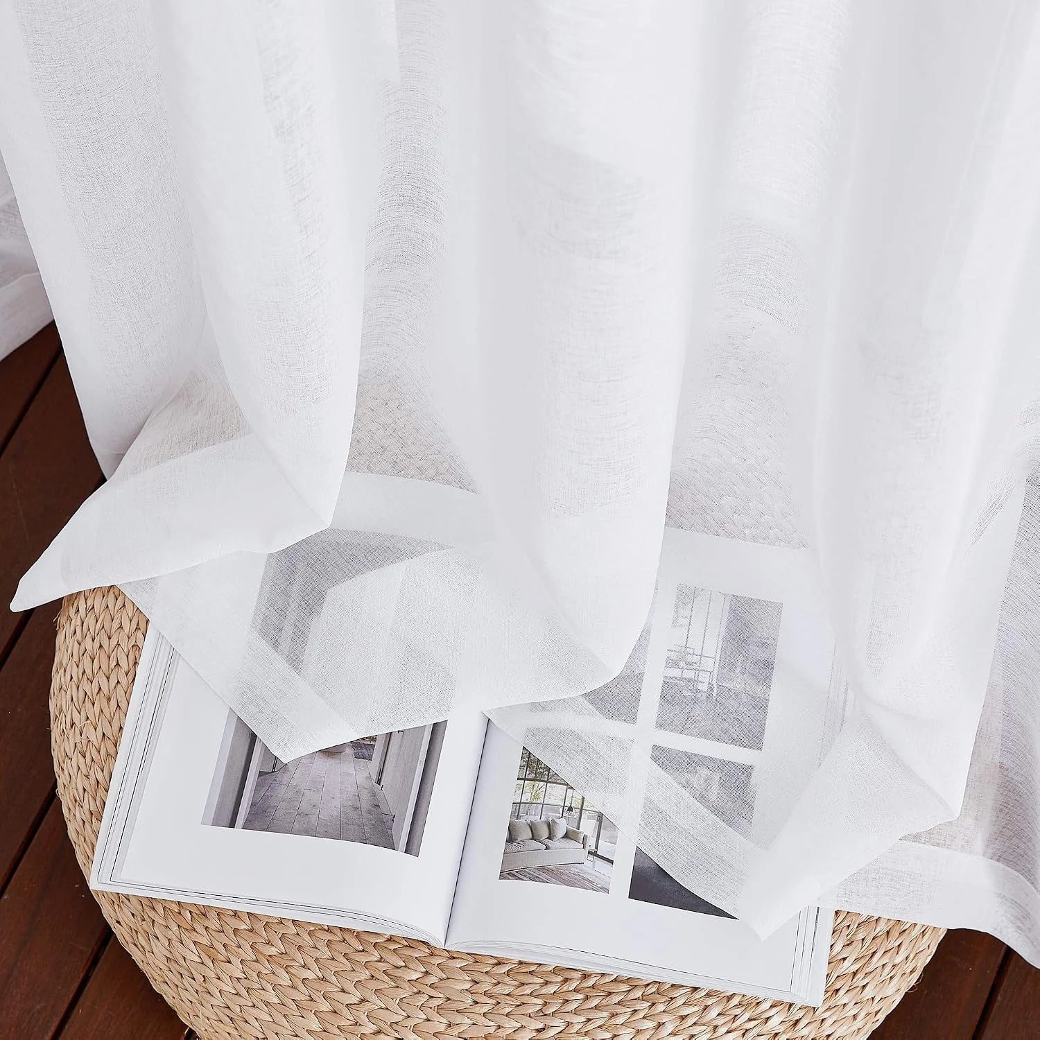 Soft white sheer linen-look curtain draped over an open book on a woven stool